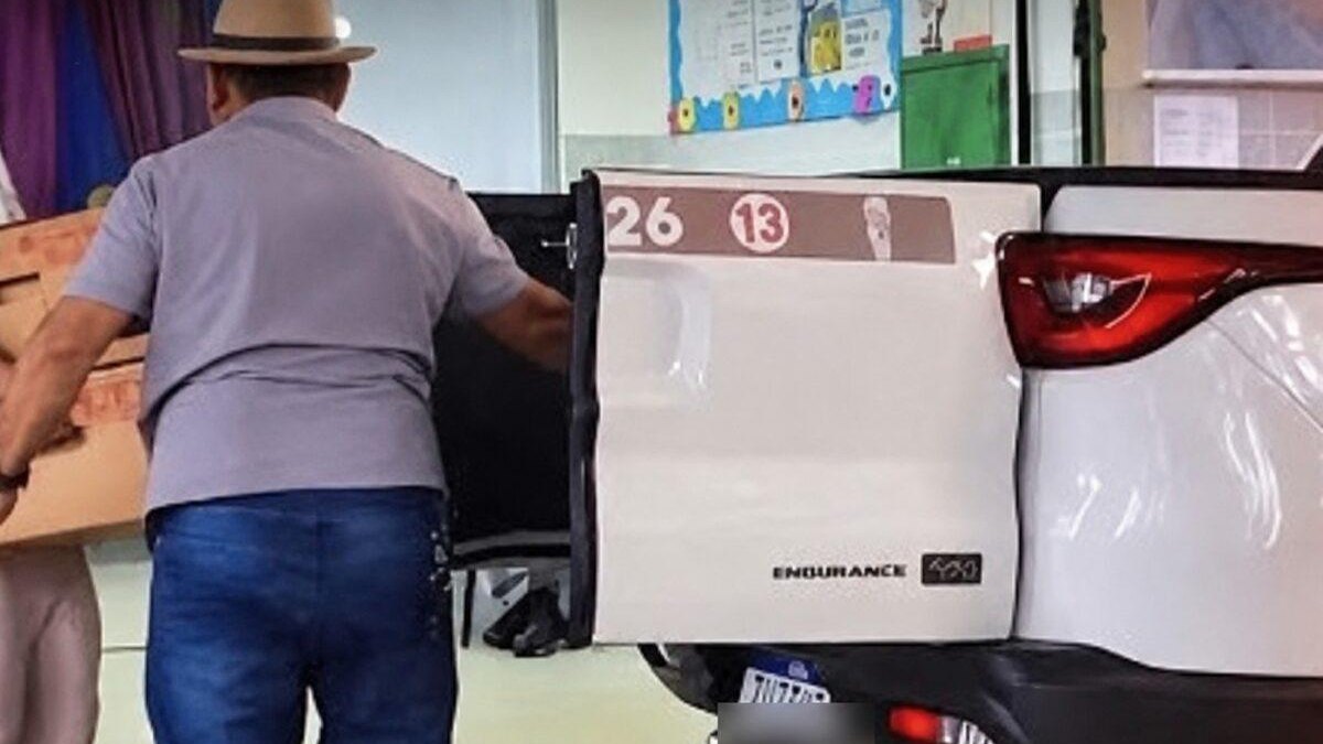 Homem coloca caixas com urnas eletrônicas em caminhonete branca com identificação partidária no Riacho Fundo II